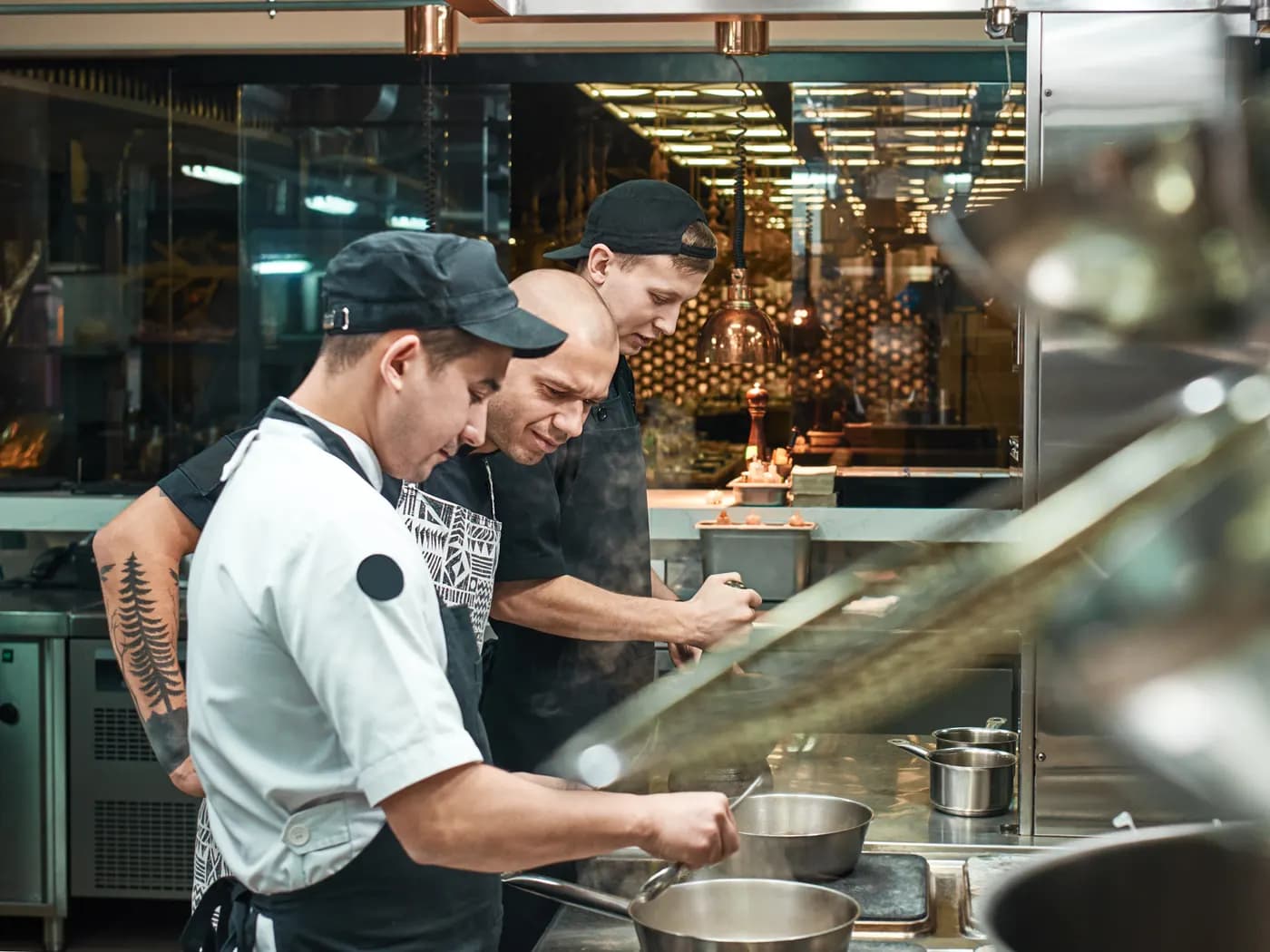 Three cooks working the line in a restaurant kitchen